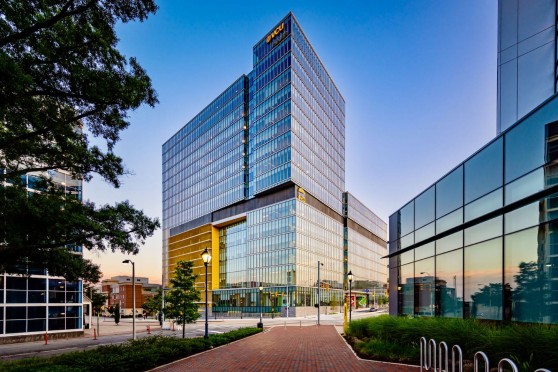 A modern high-rise office building at twilight with illuminated windows and the company logo ‘VCU Health’ at the top.