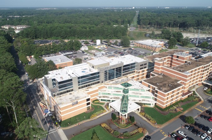 A large brick hospital building with a glass and white entrance.