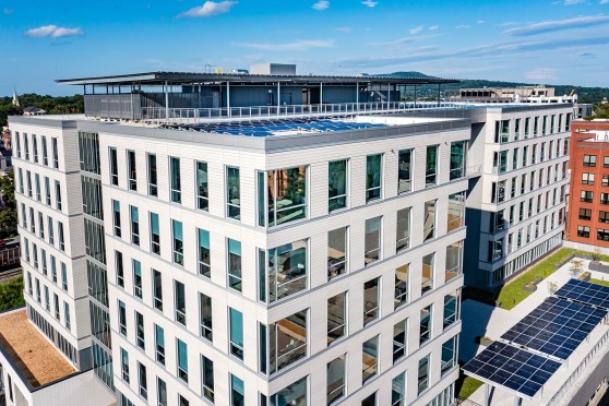 A white building with many windows, and solar panels on the roof.