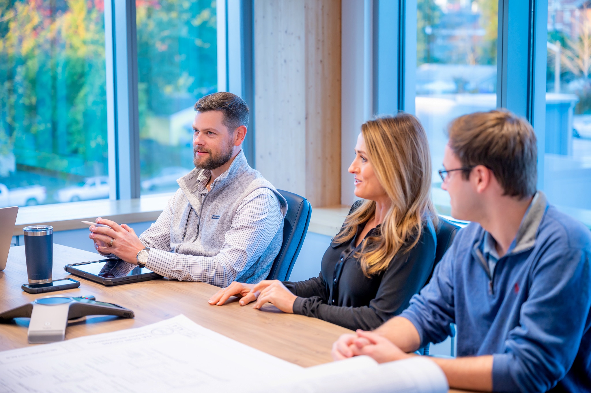 Three people sit at a conference table during a meeting.