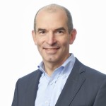 A man in a suit smiles.