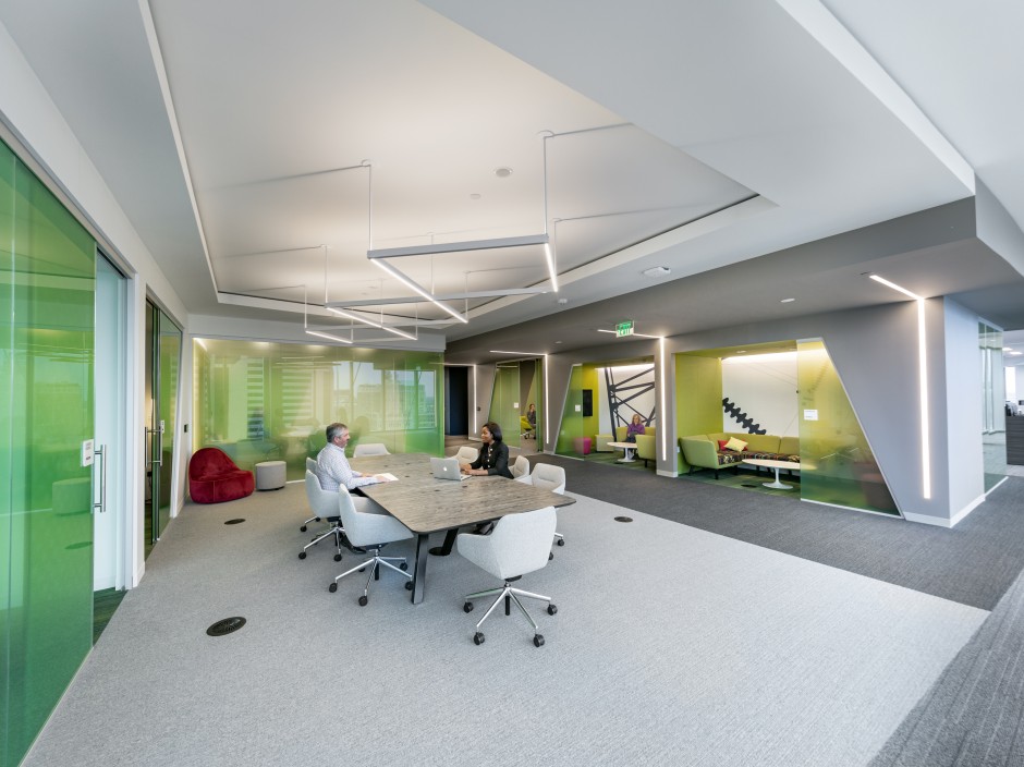 Modern office shows a meeting room with private work spaces on the perimeter.