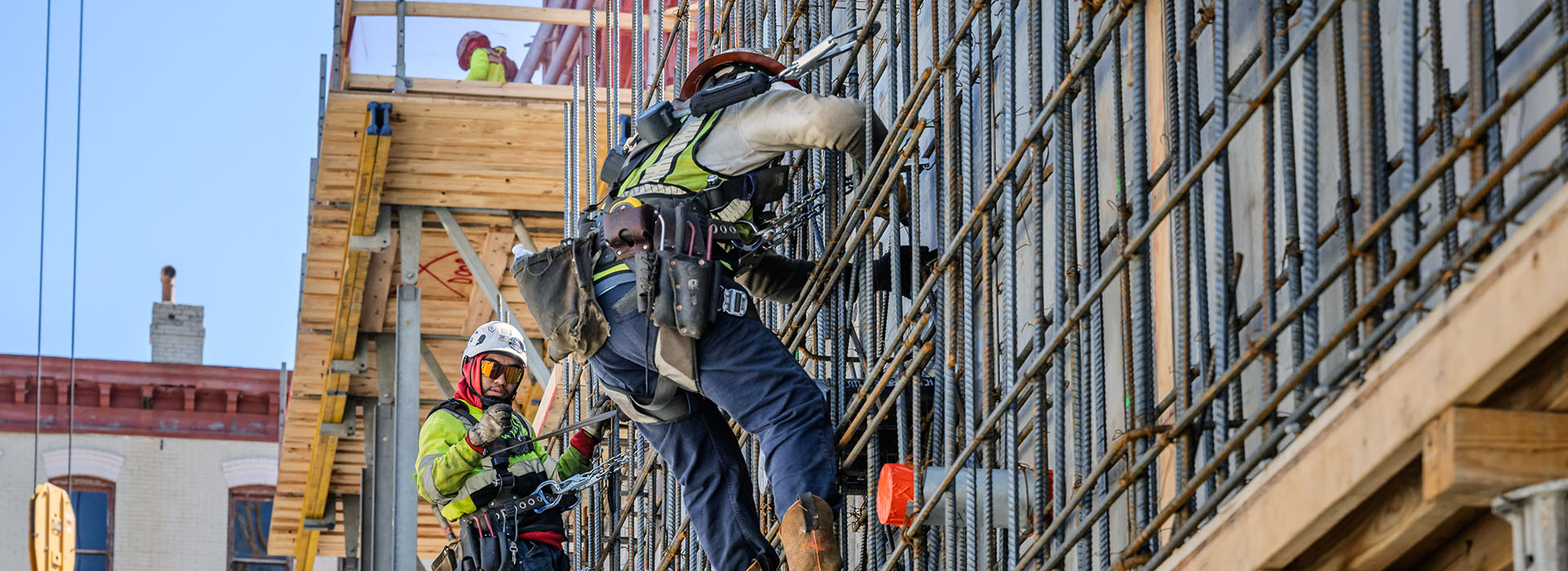 Men in safety gear climbing on metal rebar wall